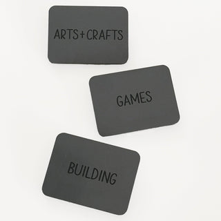Three black labels with 'Arts + Crafts', 'Games', and 'Building' text on a white background.