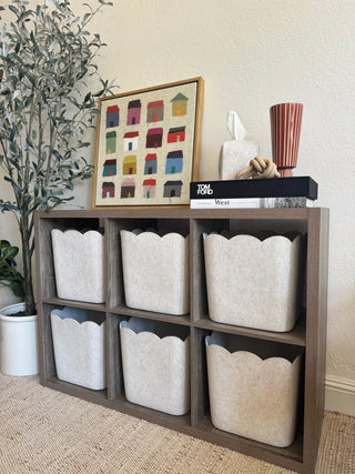 Wooden shelf with fabric rolls and a small framed artwork on a neutral background.