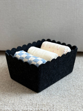Black woven basket with bath products on a neutral background