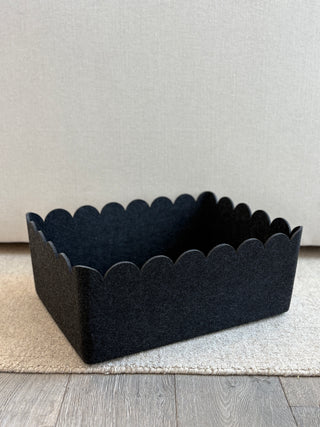 Black scalloped-edge basket on a light gray surface with a neutral background